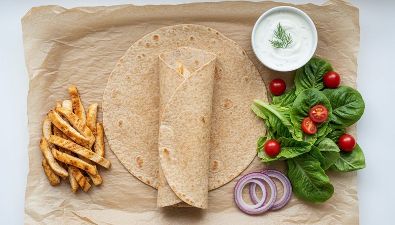Ingrédients frais d'un wrap allégé : poulet grillé, crudités, tortilla de blé complet